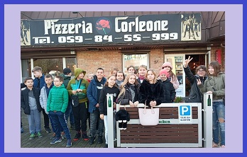 zdjęcie przedstawia uczniów klasy 5 stojących przed Pizzerią Corleone